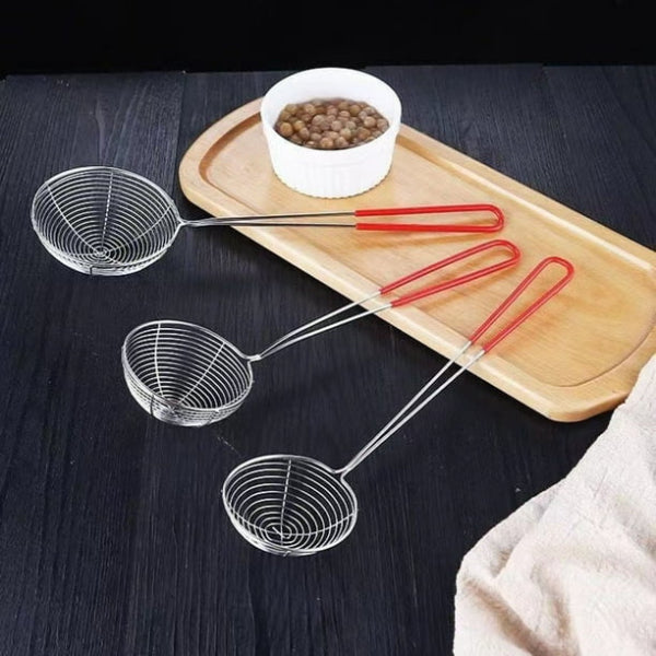 Three metal skillets with red handles on a dark surface next to a wooden tray with a bowl of food.