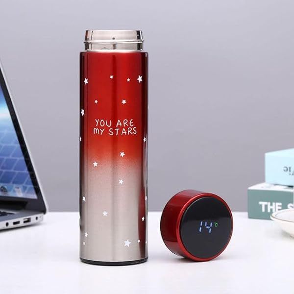 Red and silver thermos with 'You are my stars' text on a desk with a laptop and books.