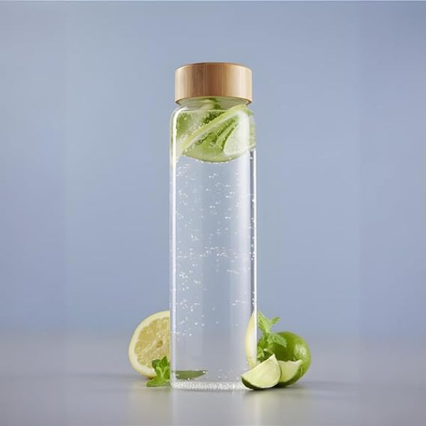 Clear glass bottle with wooden cap containing water and lime slices on a light gray background