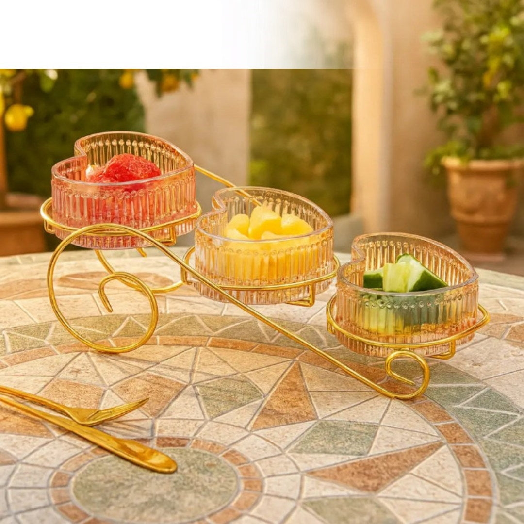 Gold three-tiered serving tray with fruit on a patterned table outdoors.