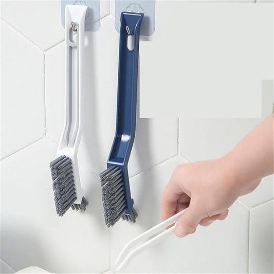 Two cleaning brushes hanging on a magnetic strip against a tiled wall.