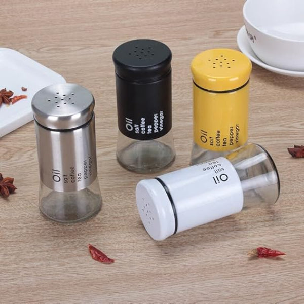 Four spice shakers in different colors on a wooden surface with dried red chilies.