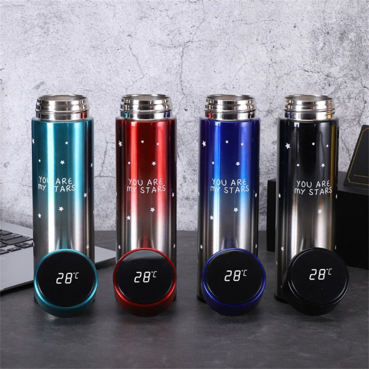 Four insulated bottles with digital temperature displays on a gray surface.