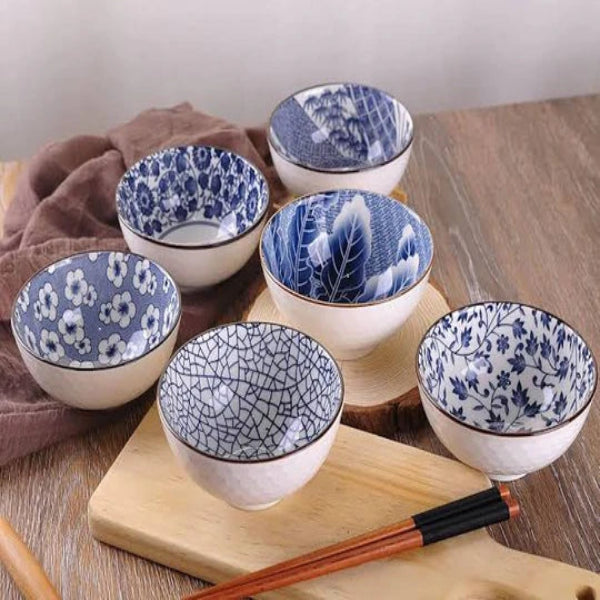 Set of blue and white ceramic bowls on a wooden surface with chopsticks.