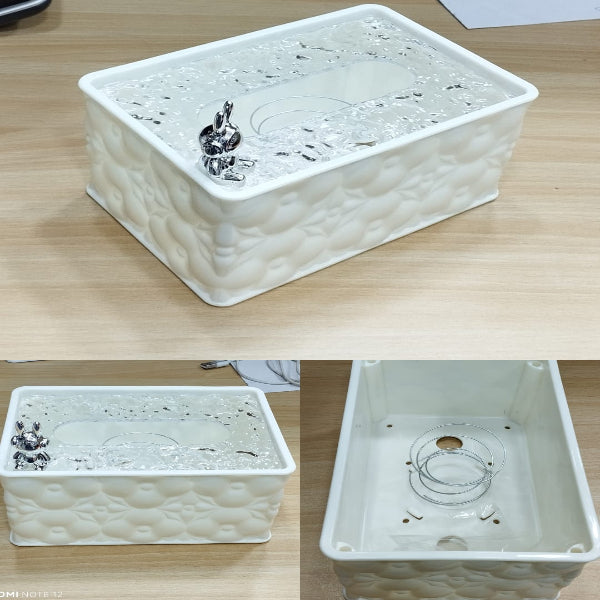 Rectangular white ceramic water fountain with decorative elements on a wooden surface.
