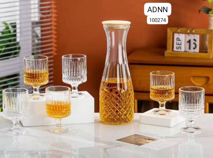 Clear glass carafe and glasses with a yellow liquid on a white surface, with 'ADNN' branding.