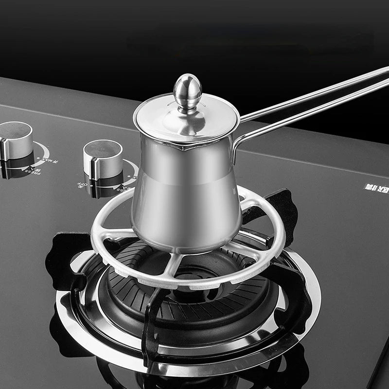 Stainless steel coffee pot on a stove with two cups nearby