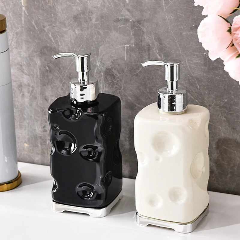 Two ceramic soap dispensers, one black and one white, on a marble surface with flowers in the background.