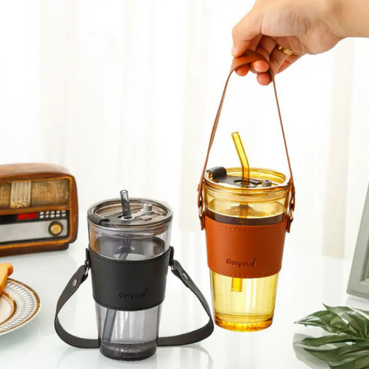 Two travel mugs with straws on a table with a radio and plant in the background.