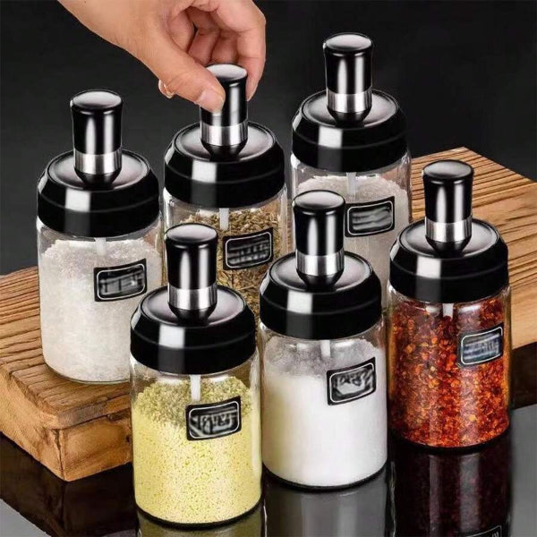 Set of glass spice jars with metal lids on a wooden surface.