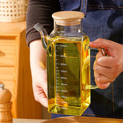 Person holding a glass oil container with a wooden lid and measurement markings.