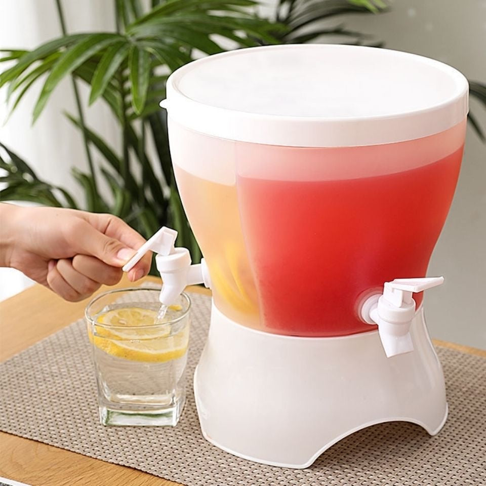 White drink dispenser with red and orange liquid, being used to pour into a glass on a table.