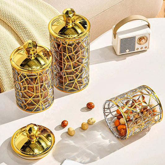 Decorative glass jars with gold lids on a light surface.