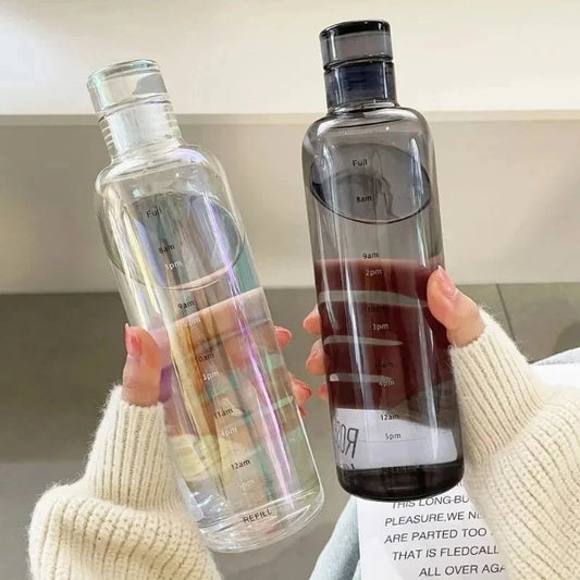 Two clear water bottles with measurement markings held by a person.