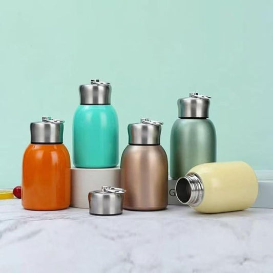 Set of colorful insulated bottles on a marble surface with a light green background
