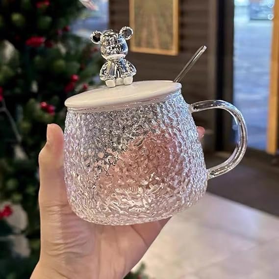 Clear textured mug with a bear-shaped handle and lid, held in a hand.