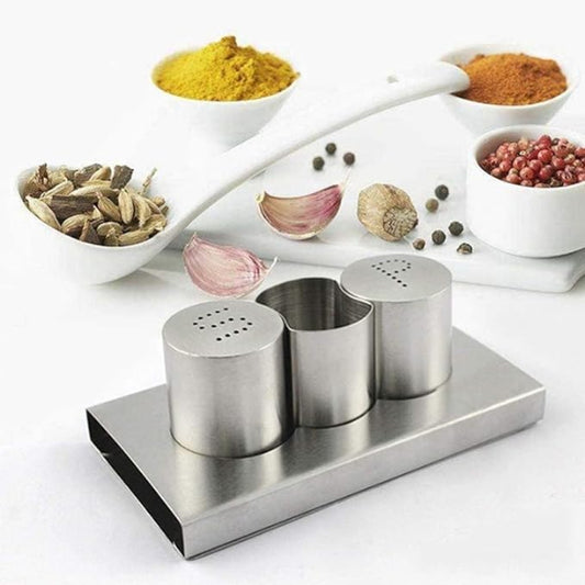 Stainless steel spice rack with three containers on a white surface, surrounded by various spices.