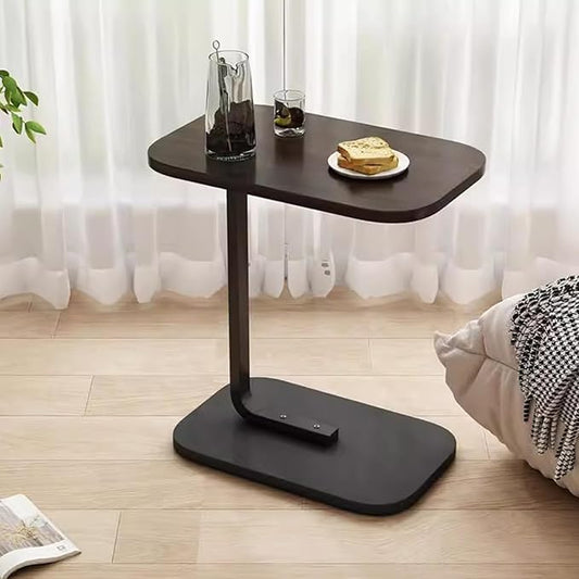 Black adjustable side table with a plate of food on a wooden floor.