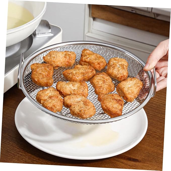 Fried chicken pieces on a metal mesh strainer over a white plate.