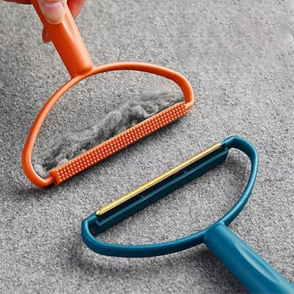 Two pet grooming tools, one orange and one blue, on a textured gray surface.