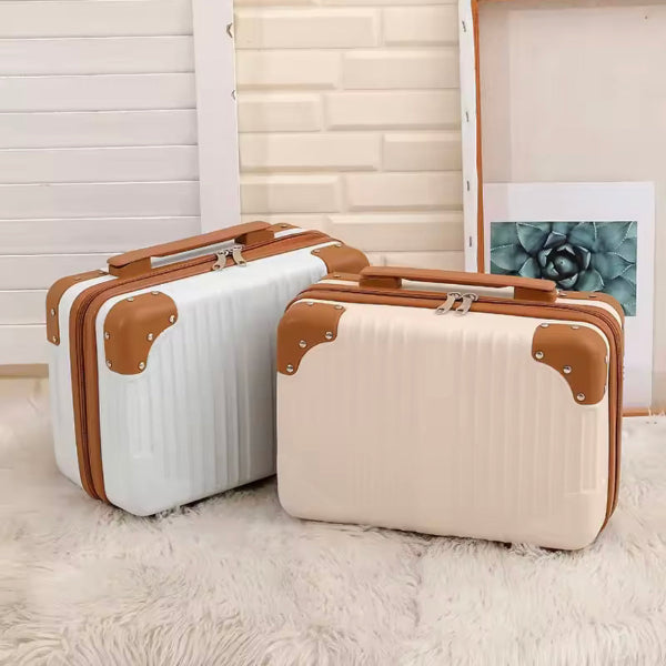 Two white suitcases with brown handles and corners on a light wooden floor.