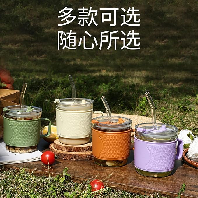 Four glass cups with colorful sleeves and straws on a wooden surface outdoors.