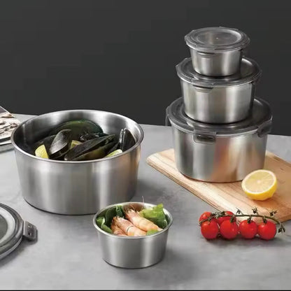 Set of stainless steel food containers with fresh vegetables on a gray surface