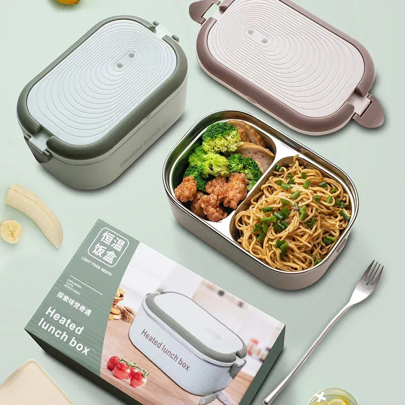 Heated lunch box with compartments of food, including noodles and vegetables, on a light green background.