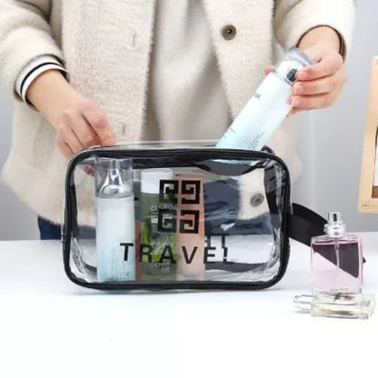 Person holding a transparent travel bag with cosmetic items on a white surface