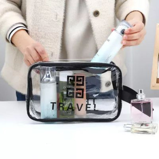 Person holding a transparent travel bag with cosmetic items on a white surface