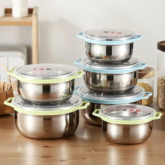 Set of stainless steel food containers with colorful lids on a wooden surface.