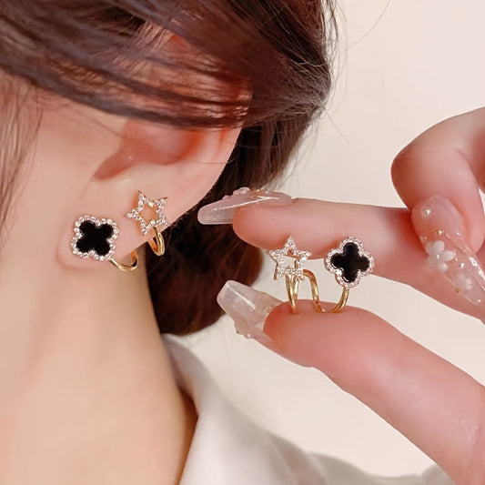 Close-up of a person wearing a star-shaped earring with a black center, held by a hand.