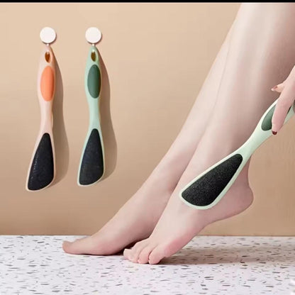 Person using a foot scrubber on their leg with two additional scrubbers on a beige background