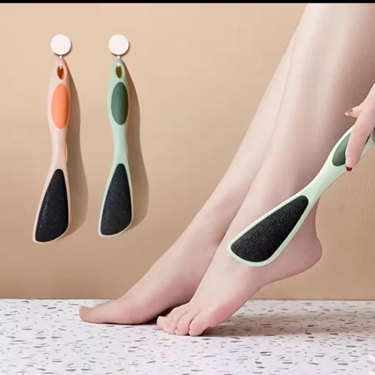 Person using a foot scrubber on their leg with two additional scrubbers on a beige background
