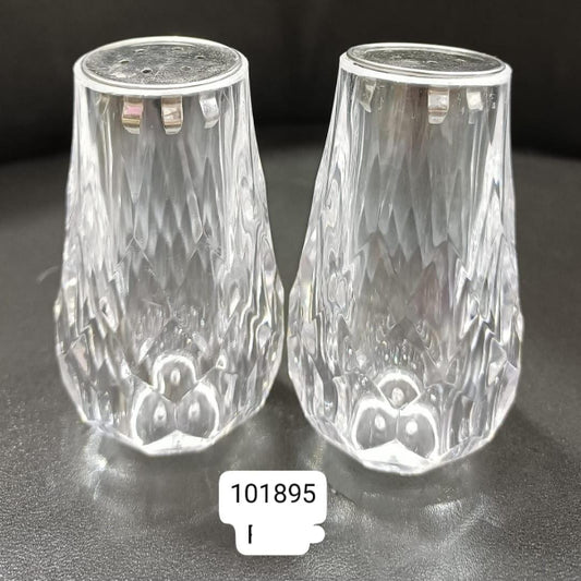 Two clear glass salt and pepper shakers on a dark surface with a label '101895'.