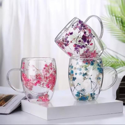 Set of clear glass mugs with floral decorations on a white surface.
