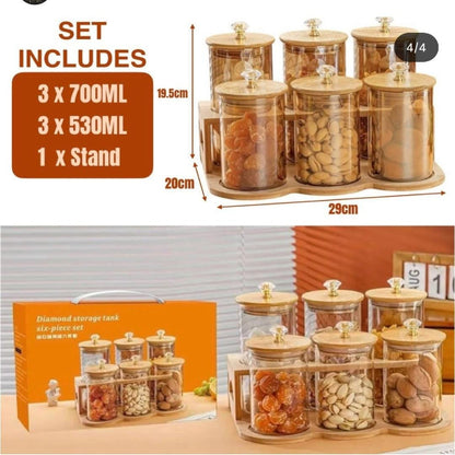 Glass storage jars with wooden stands and included items displayed on a table.