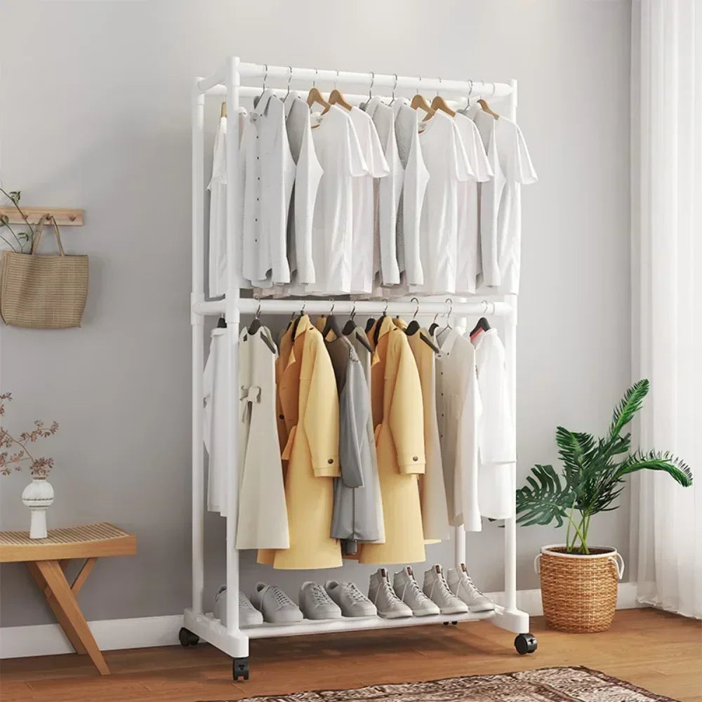 Clothing rack with clothes and shoes in a room with a plant and small table.