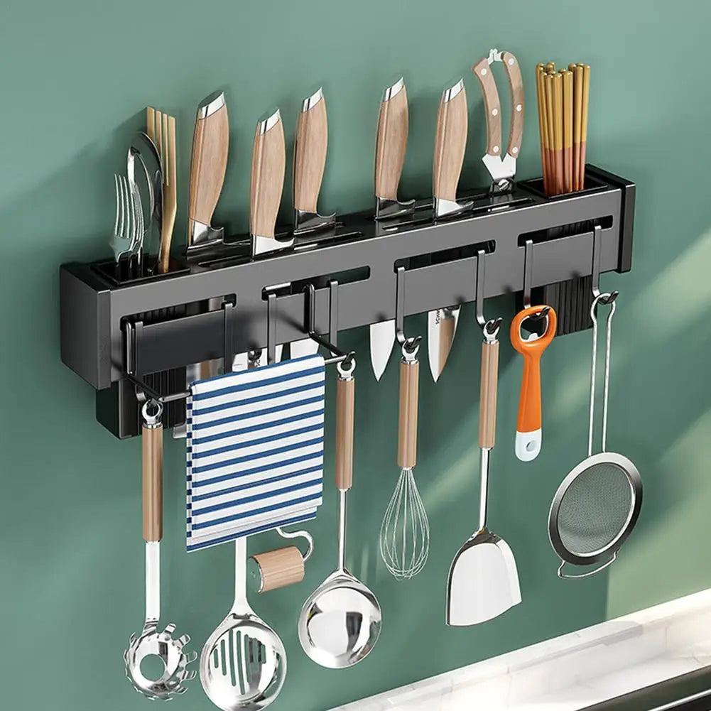 Wall-mounted kitchen utensil holder with various utensils on a green wall.