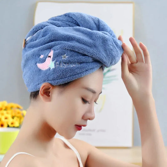Woman wearing a blue towel with a cartoon design on her head, holding a white object.
